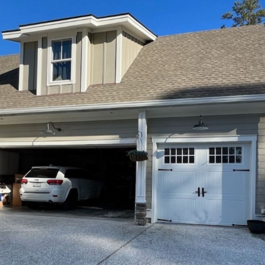 Professional gutter installers from Spartina Seamless Gutters using a tall extension ladder to install custom-colored seamless gutters on a modern two-story board and batten home in Isle of Hope, GA.