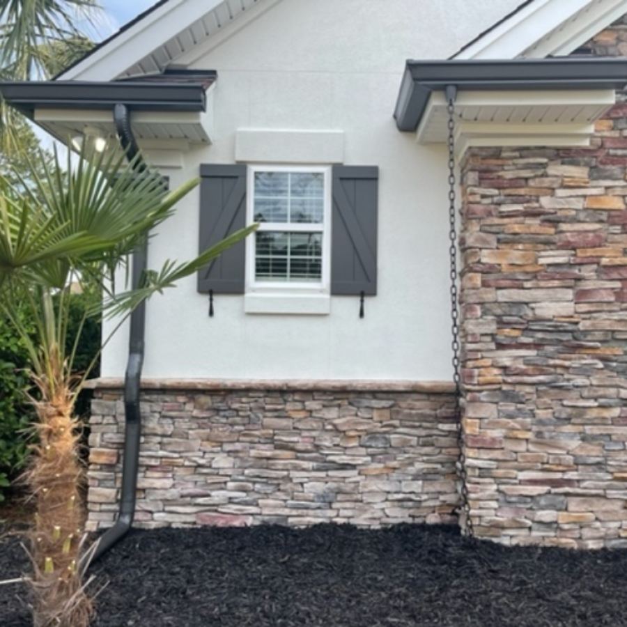 Spartina Seamless Gutters installation on a stone and stucco home in Montgomery, GA, featuring dark gutters and a decorative rain chain