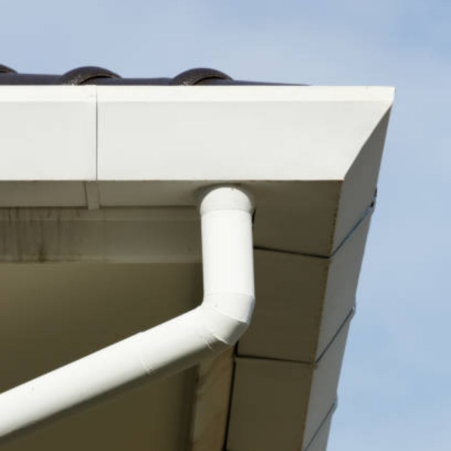 Commercial building in Sandy Springs, GA featuring white Spartina seamless gutters and angled downspout along a clean fascia under a partly cloudy sky.