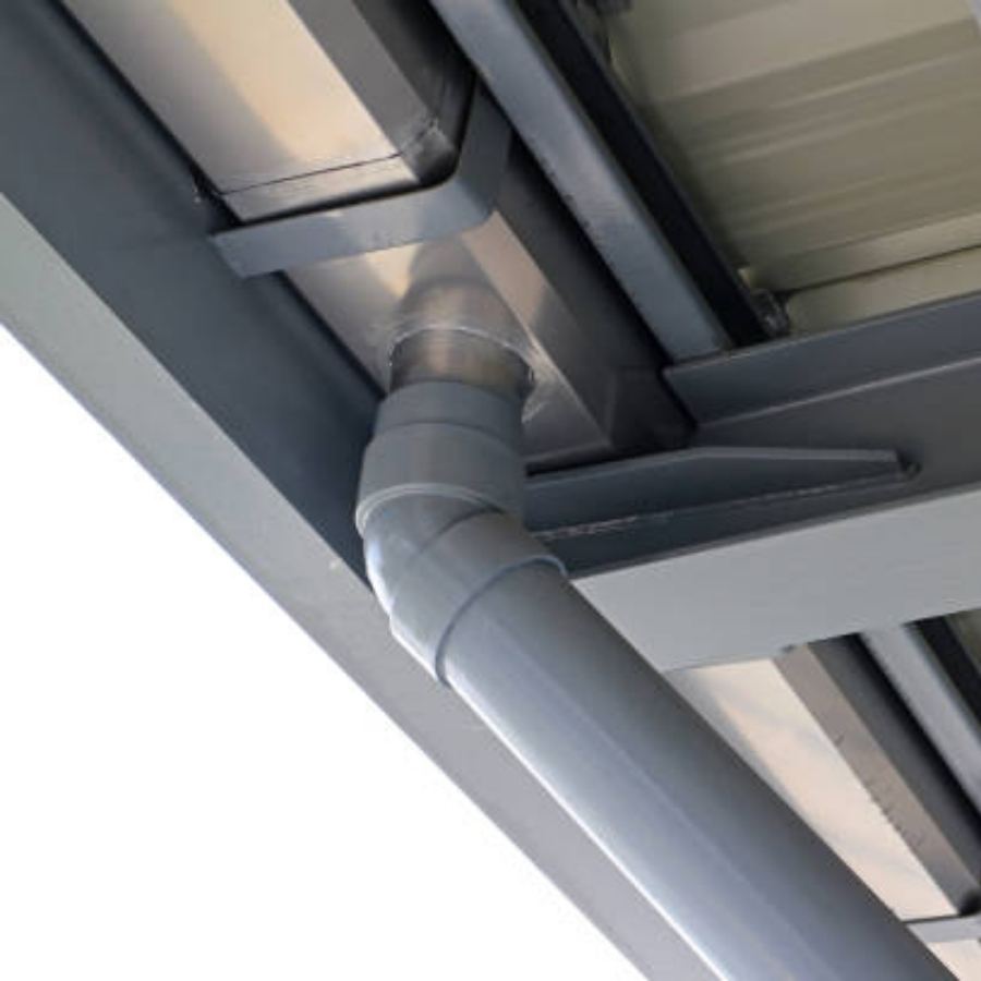 Close-up underside view of Spartina seamless gutters and round downspout on a commercial metal building in Savannah, GA, highlighting durable joints and modern drainage design.