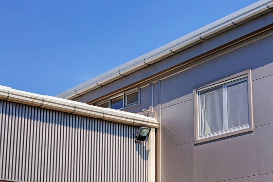 Modern commercial buildings in Athens, GA featuring Spartina seamless gutters along the rooflines, with metal siding, windows, and clear blue sky in the background.