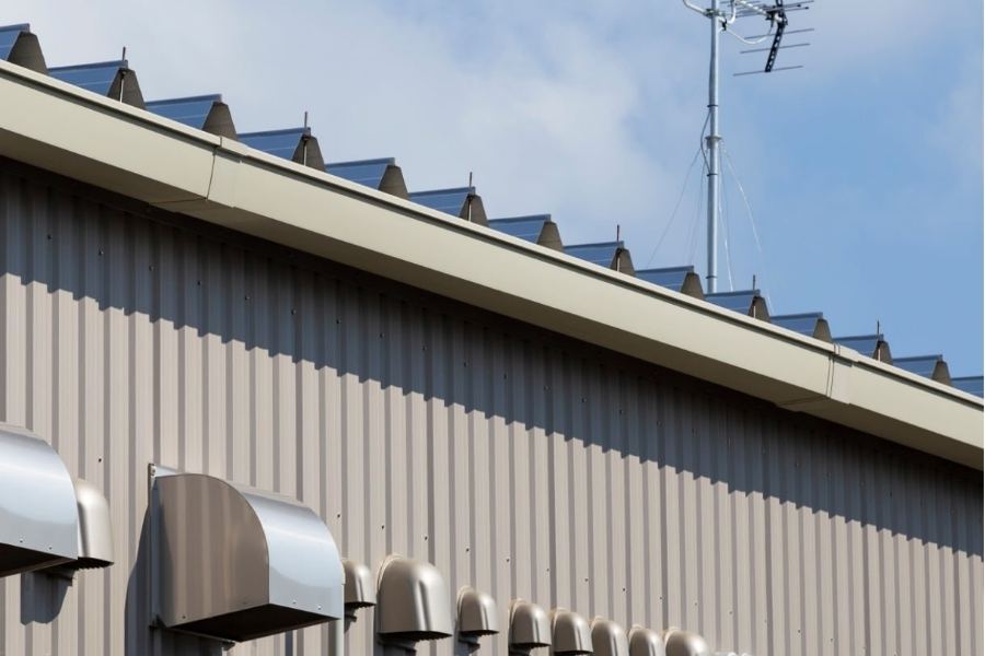 Commercial metal building in Charleston, SC with Spartina seamless gutters along the roofline, showing durable drainage system and exterior vents against a blue sky.