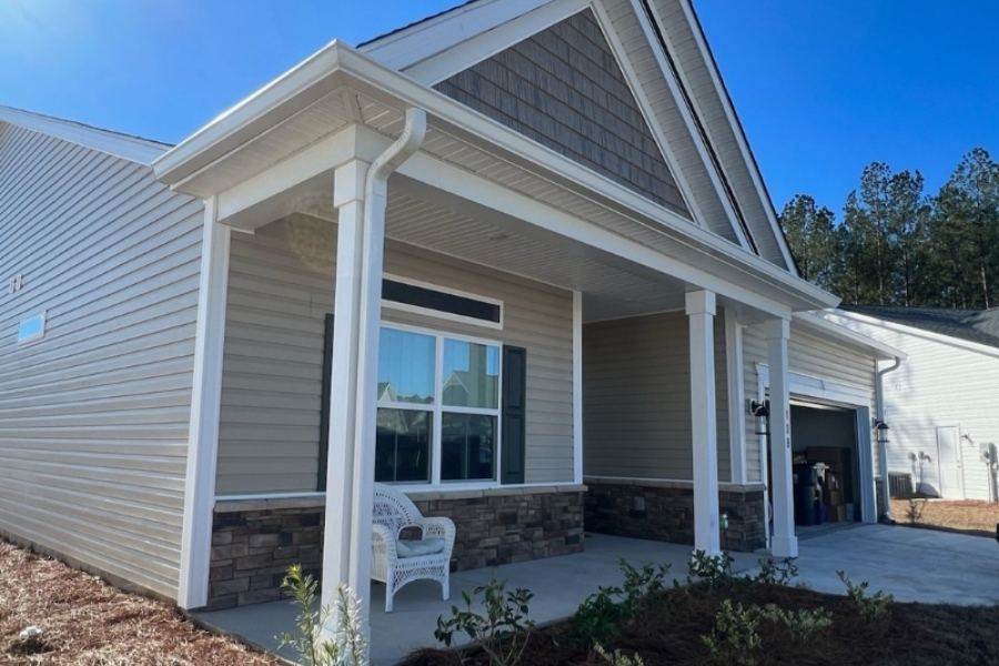 Professional installation of white seamless gutters and downspouts by Spartina Seamless Gutters on a craftsman-style home with tan siding and stone accents in Montgomery, GA.