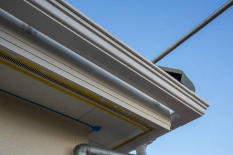 Commercial building in Sandy Springs, GA with Spartina seamless gutters, soffit vents, and exposed utility conduits along a decorative cornice under a clear blue sky.