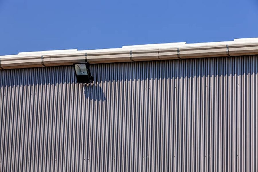 Commercial metal building in Sumter, SC featuring Spartina seamless gutters along the roofline and corrugated steel siding under a clear blue sky.